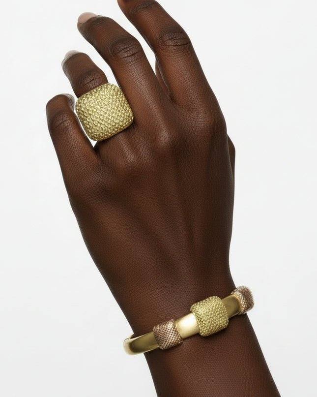 Gold jewelry set including necklace, bracelet, and ring on black mannequin hands with a marble background.